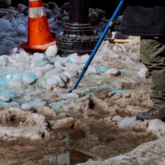 Cleaning the yard of snow. man in a jacket and boots, holding a plastic shovel with snow, Workers sweep snow from road in winter, Cleaning road from snow storm, Selective focus