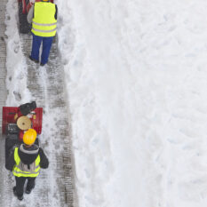 Workers cleaning snow on the sidewalk with a snowblower. Maintenance