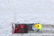 Worker cleaning snow on the sidewalk with a snowblower. Maintenance