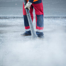 Worker with leaf-blower, cleaning out the dust for better asphalt adhesion, during tram track renewal works