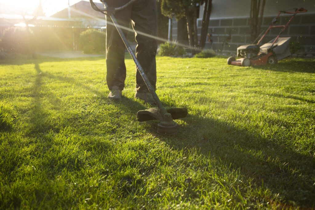 Garden worker using a lawn mower during spring garden maintenance.